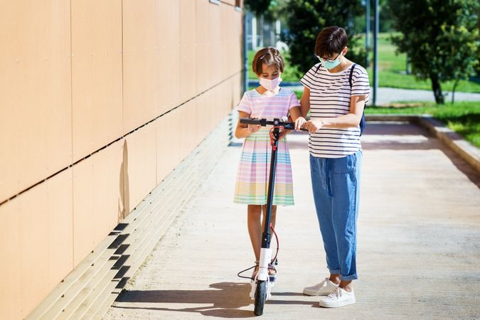 Girl on scooter with mother by her side