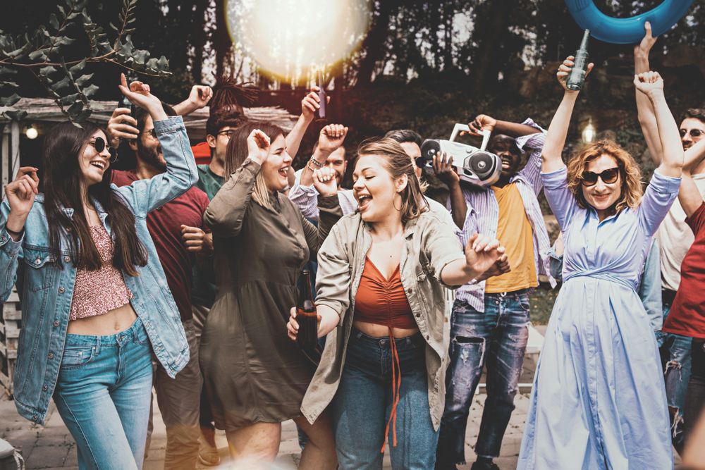 Large multi-ethnic group of friends having fun dancing outdoors