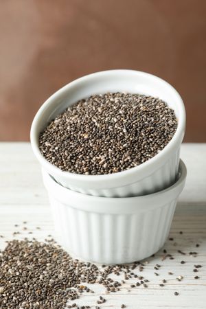 Ceramic sauce boats with chia on wooden background, copy space