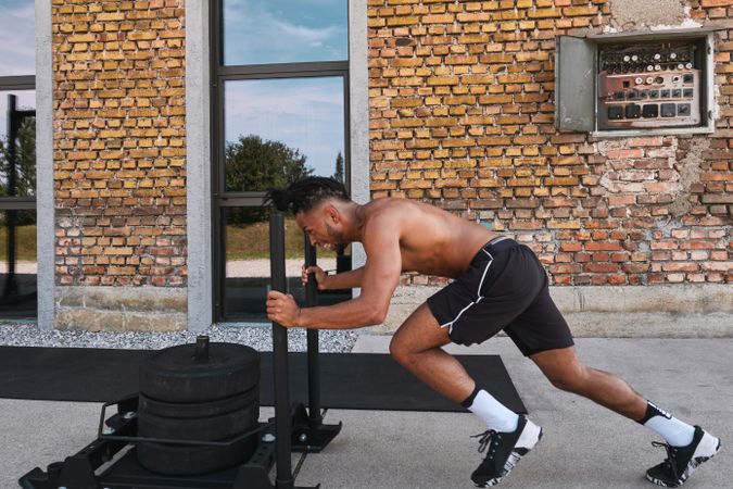 Black guy pulling weights in outdoor gym