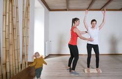 Trainer helping mother with exercise
