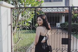 Woman in dark dress standing near dark dark metal gate