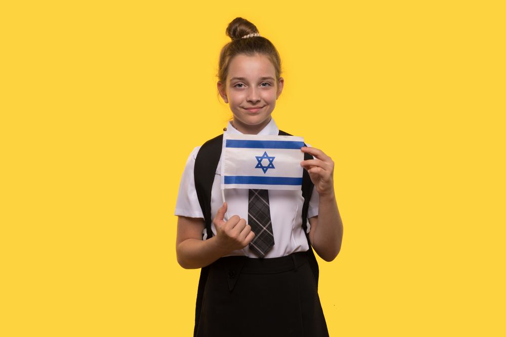 Schoolgirl proudly holds the Israeli flag while posing.