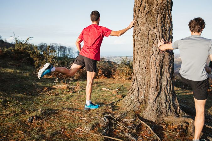 Active men warming up before running in mountains