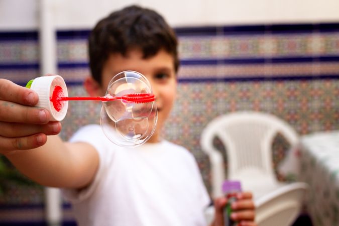 Boy playing with soap bubbles on terrace