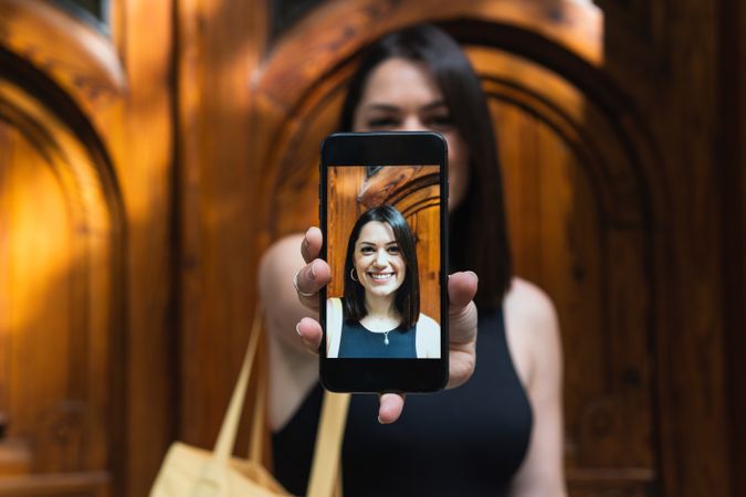 Delighted woman taking selfie on smartphone in city