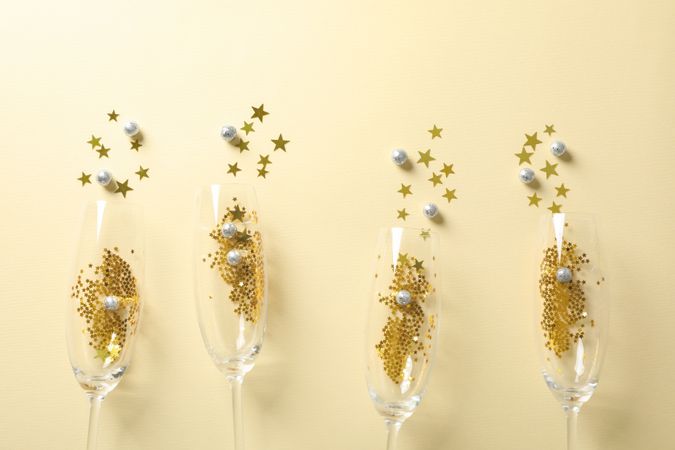 Champagne glasses with glitter on beige background, space for text