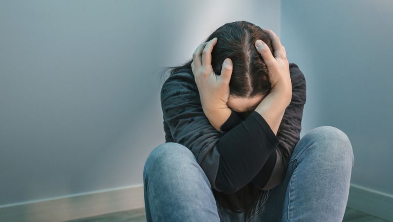 Unrecognizable woman holding head in great distress