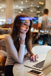 Brunette woman in a restaurant working on her laptop