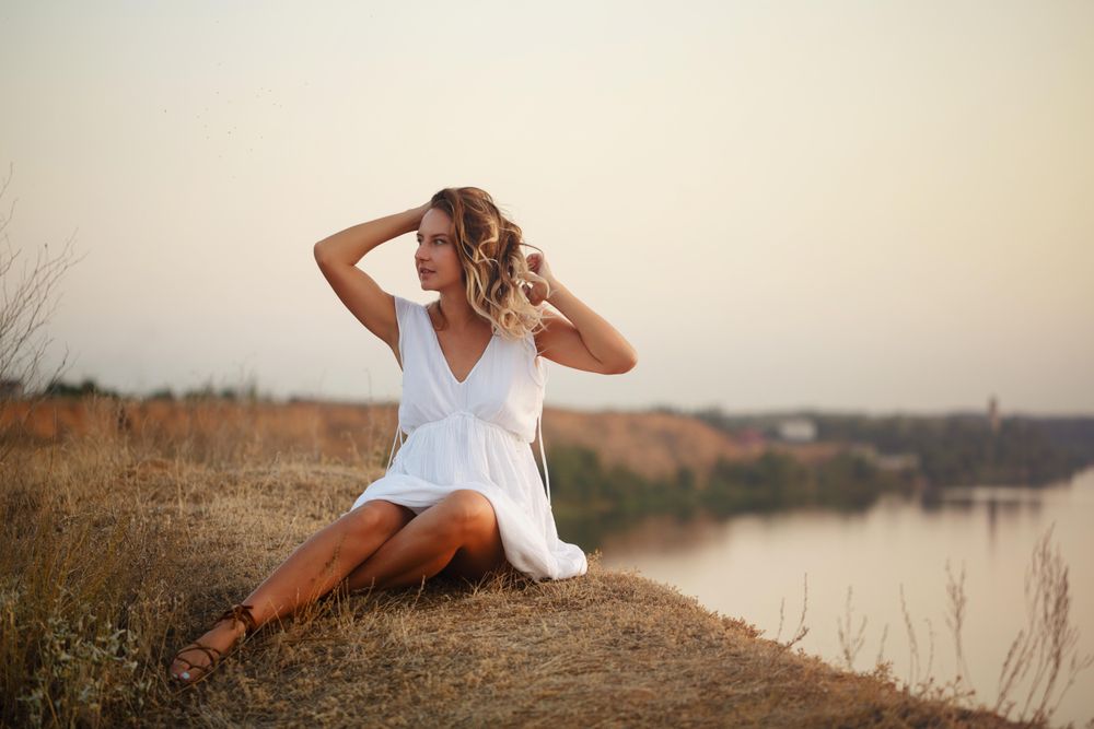 Female in summer dress relaxing by the lake at dusk