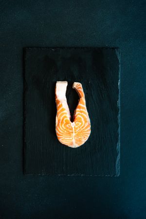 Top view of single salmon steak on dark kitchen counter