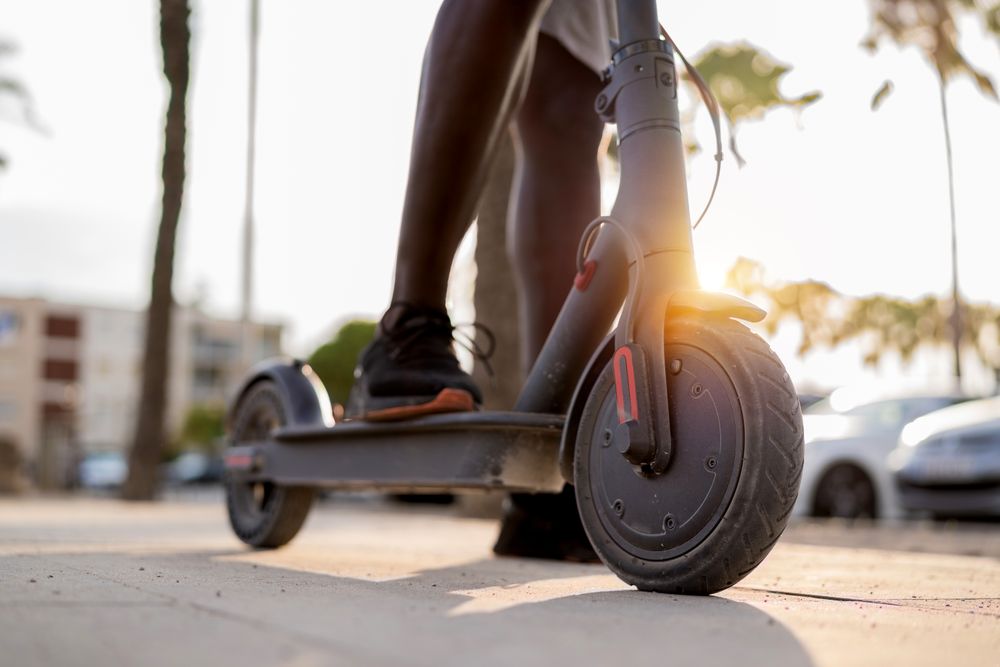 Black man riding scooter in street