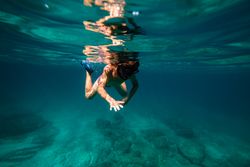 Teen boy snorkeling in deep seawater in flippers and mask