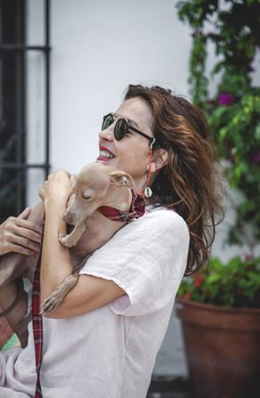 Woman kissing greyhound while relaxing on street