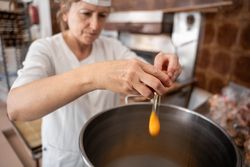 Baker woman adding eggs to a big industrial pan to prepare cupcakes
