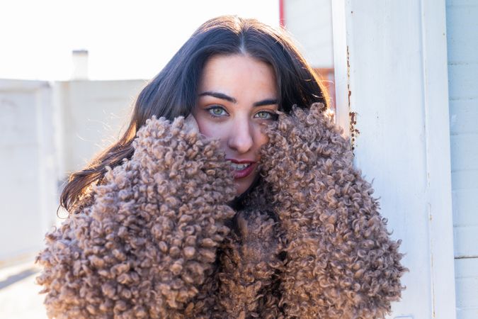 Cheerful woman wrapping in coat on street