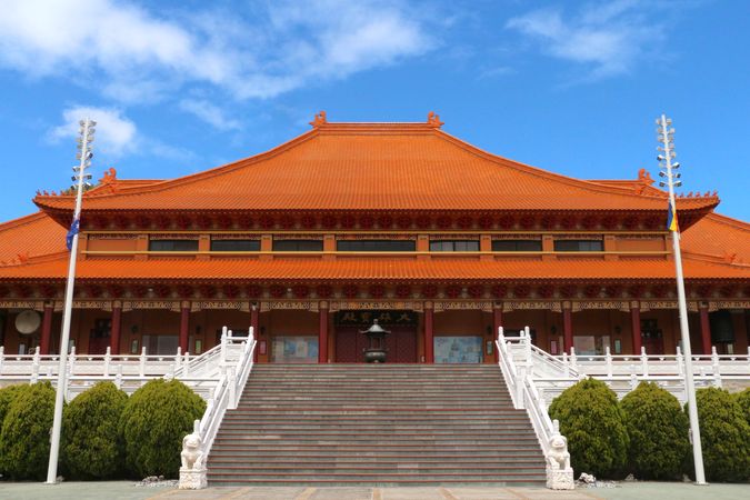 Beautiful temple with traditional architecture and vibrant orange roof situated in a serene location surrounded by greenery