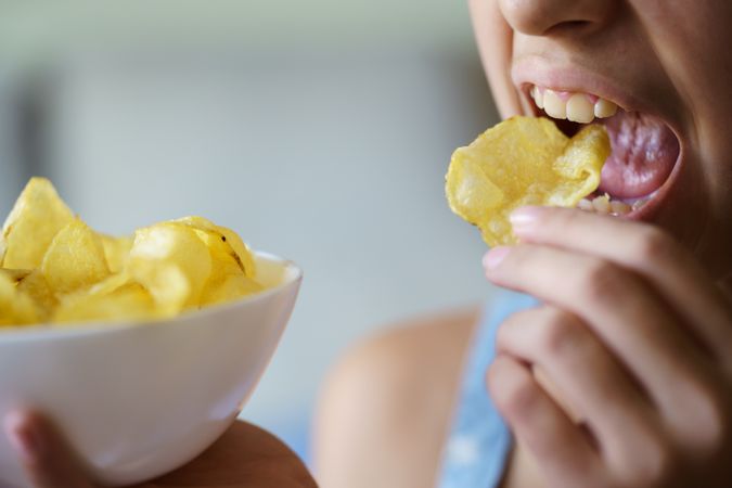 Teenager opening mouth to snack on potato chips
