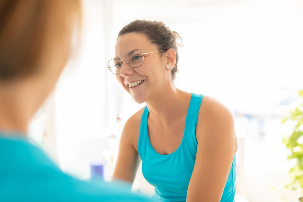 A woman patient talks cheerful to her physiotherapist after receiving a manual therapy session