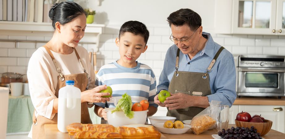 Asian grandparents support and help grandson cooking breakfast in the kitchen