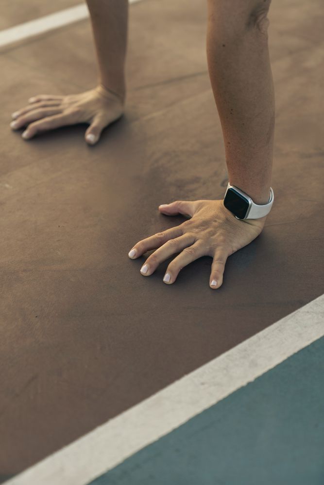 Close up of a woman's hands in a press-up position, tracking her workout with a smartwatch