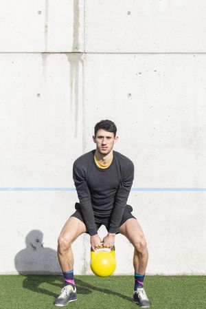 Man training with kettlebell on lawn