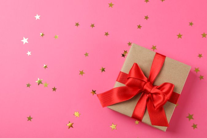 Gift box with bow on decorated pink background, space for text