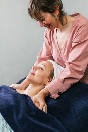 Smiling masseuse doing massage for woman in spa salon
