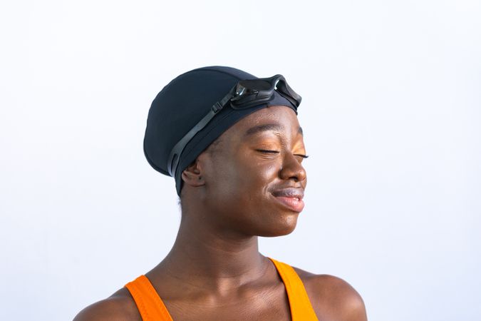 Portrait of a Black young woman in swimsuit with closed eyes with plain background