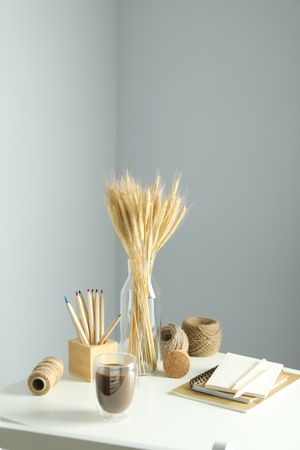 Work table with yarn, notebooks, pencils, dried flowers, vertical