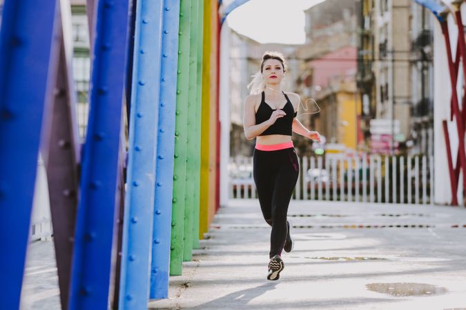 Woman with earphones running on street