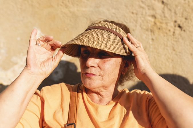 A older woman adjusts her cap to protect herself from the sun as she enjoys the afternoon in Galicia, Spain
