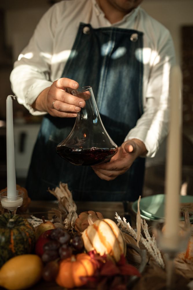 Man in apron holding a pitcher standing beside pumpkins on a table