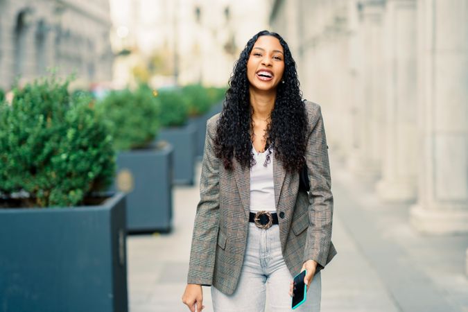 A Stylish Young Woman Smiling Happily Outdoors in a Vibrant Urban Setting Full of Life