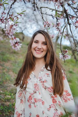 Young happy woman between trees in garden