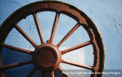 Close up of old iron wheel on blue wall 4jkyRb