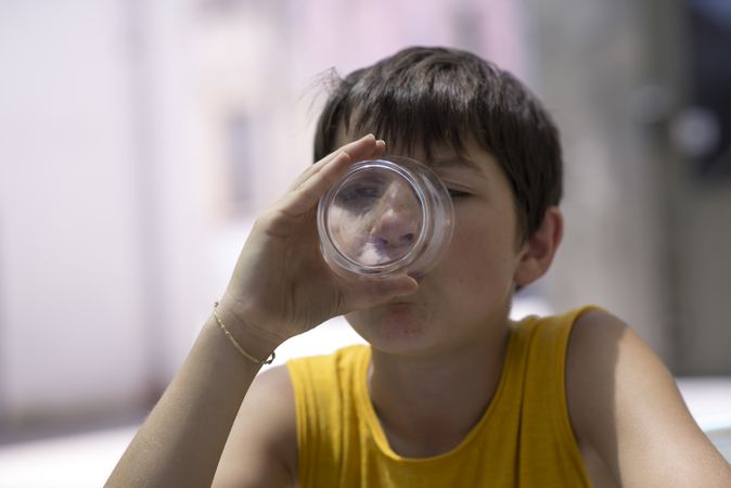 Teen boy drinking a glass of pure water