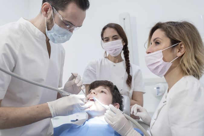 A portrait of a dentist with his team working in the background