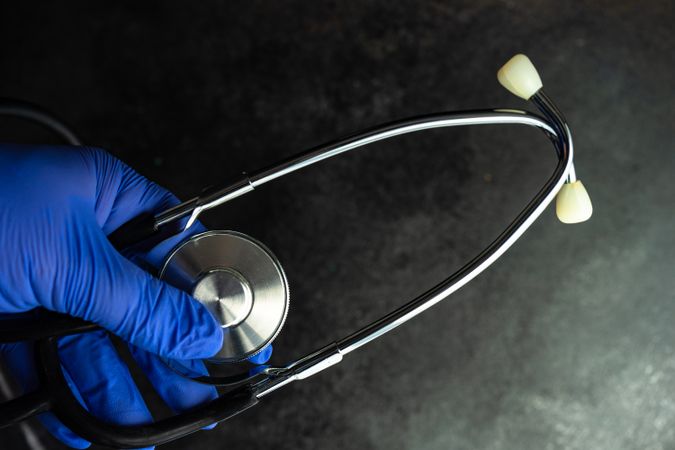 Top view of hands wearing purple latex gloves holding a medical stethoscope