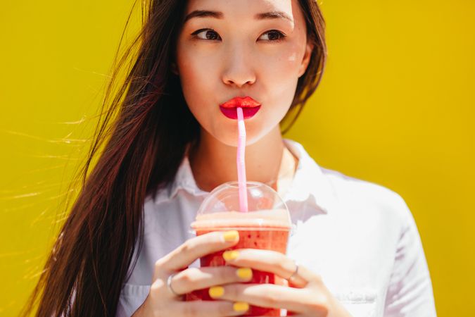 Portrait of a young woman enjoying a smoothie outdoors