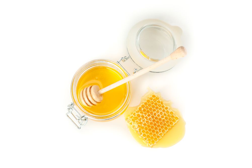 Glass jar, honeycomb and dipper isolated on neutral background