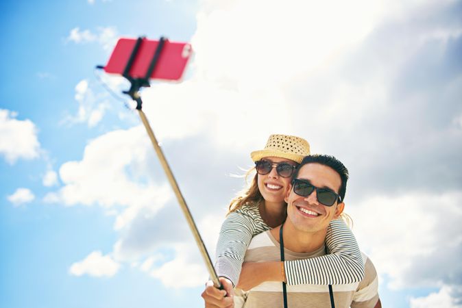 Happy couple with selfie stick on nice day