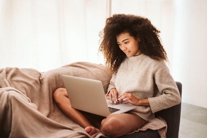 Black female using laptop on sofa