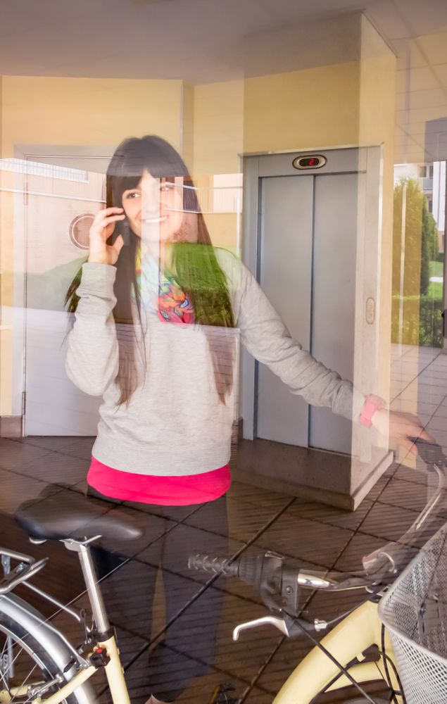 Female with fixie bike leaving hall behind a glass