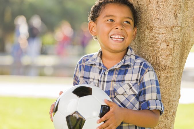 Laughing Boy Holding Soccer Ball in the Park