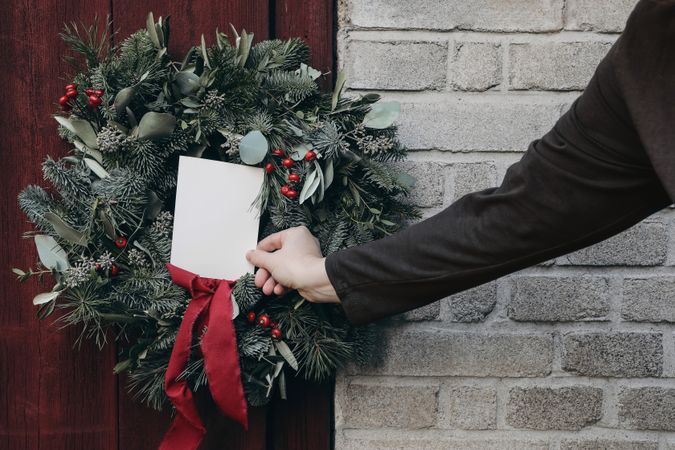 Person putting card on Christmas advent wreath