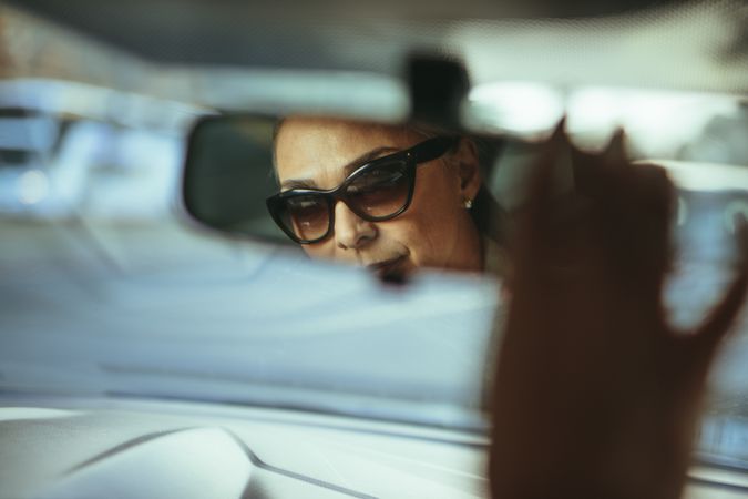 Reflection in rear view mirror of older woman wearing sunglasses