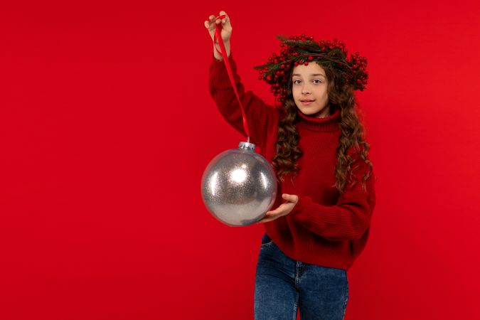 Teen girl in Christmas berry wreath posing with silver bauble.