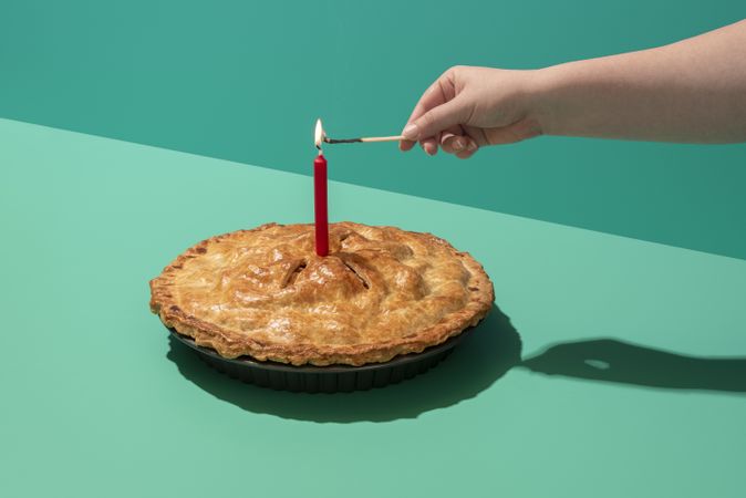 Festive apple cake with a lit candle, minimalist on a green table