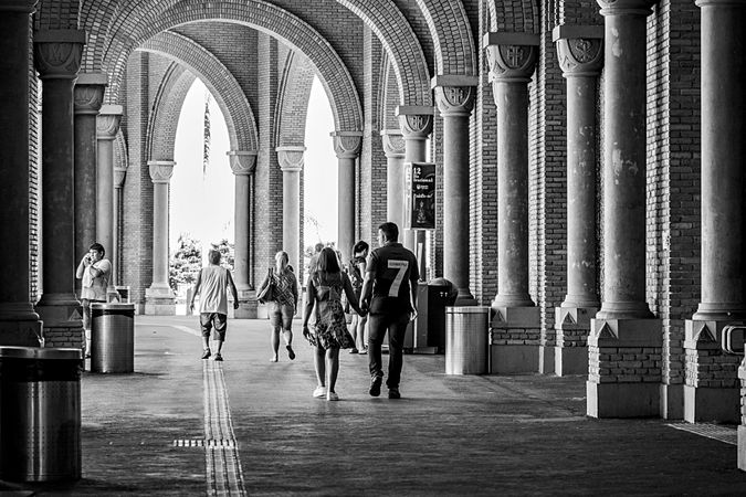 Grayscale photo of people walking in hallway